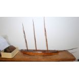 A scale model of a schooner in mid restoration, the solid hull sits in a carved wood ocean,