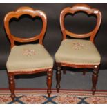 A pair of Victorian balloon back dining chairs, each with a floral woolwork seat and on turned legs.