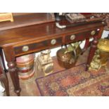 A Victorian mahogany writing table with two drawers on turned fluted legs.