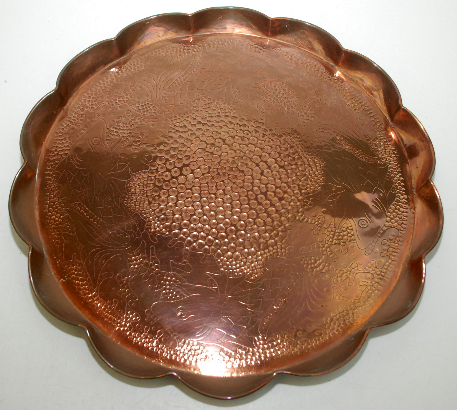 A J F Pool, Hayle, circular copper tray engraved with fish about a planished centre, shaped rim,