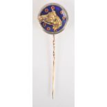 A gold and enamel jockey's pin with a blue enamel disc rimmed with platinum,