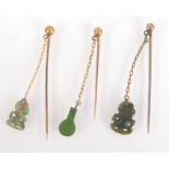 Two New Zealand gold pins each suspended with a green stone tiki and one other similar pin.