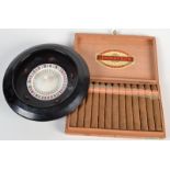 A black and white plastic roulette wheel, together with a full box of Jamavana Cigars.