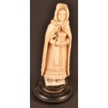 A late 19th century or early 20th century Dieppe ivory figure of a pious lady holding a prayer book,