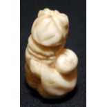 A Japanese ivory netsuke, carved with a boy hugging a column surmounted by a bag, height 3.5cm.