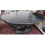 An oval ebonised dining table on four shaped supports, length 143cm.