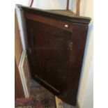 A George III oak hanging corner cupboard with panelled door.