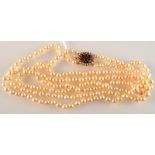 A long double strand cultured pearl necklace, the 9 ct gold clasp set red stones and pearls,