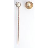 A gold pin with a screw in half pearl finial surrounded by tiny diamonds, boxed with a single stud.