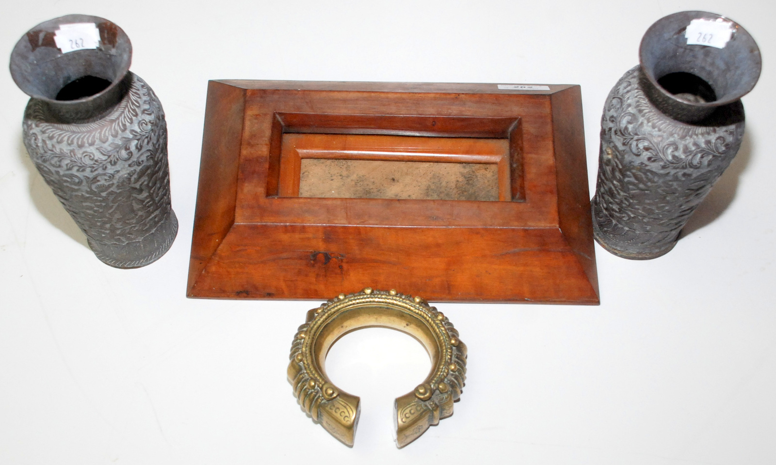 A small frame, a pair of Indian chased copper vases and a heavy African brass bangle.