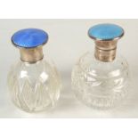 Two cut glass toilet bottles, each with blue enamelled silver lid.
