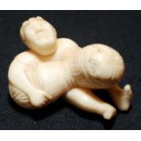 A Japanese ivory netsuke, of a man carrying a large bundle, width 3.5cm.