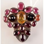 An Arts and Crafts silver clip set with cabouchon garnets, and a faceted citrine.