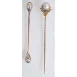 A gold pin with pearl and diamond set ribbon finial.