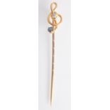 A high purity gold treble clef pin set a diamond and a sapphire, boxed.