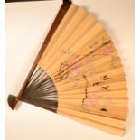 A large Japanese paper fan painted with flowering branches and birds in flight, hardwood frame,