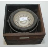 A ship's brass compass on a gimbal mount, now mounted in a hardwood box,