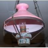 A large Victorian pendant brass oil lamp with a marbled glass font and pink shade.