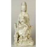 A late 18th century Fukien Dehua figure of a seated Quanyin supporting a child acolyte on her lap,