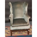 A George III style upholstered wing armchair.
