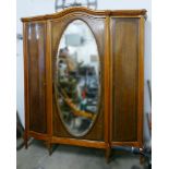 An early 20th century French armoire of mahogany framed serpentine form, the arched pediment with