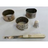 Three silver napkin rings, a silver and mother-of-pearl handled fruit knife and a silver thimble (