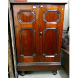 A Victorian panelled mahogany two door cupboard on turned feet, formerly housing a commercial