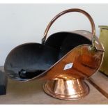 A beaten copper coal scuttle with shovel