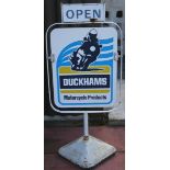 A Duckhams Motorcycle Products swivel sign, together with two swivel stands, with cast iron bases (