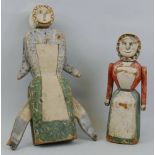 Two 19th century painted pine dolls, both naively carved wearing aprons one as a woman with two