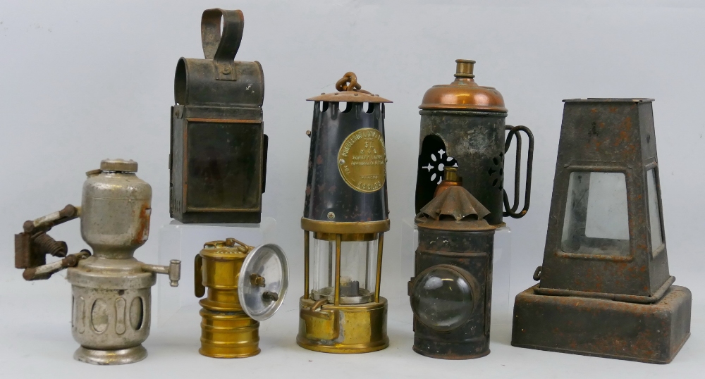 Seven various hand lamps, including miner's brass and steel safety lamp by The Protector Lamp and