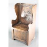 A carved oak lambing style seat with arcaded carved decoration to the back, the base fitted a recess