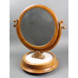 A Victorian circular bevelled plate dressing table mirror contained in a mahogany swing frame,