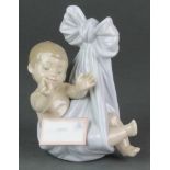 A Lladro figure of a baby in a tied blanket holding a letter A28JU 5 1/2"