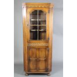 An "Ipswich" style oak double corner cabinet, the upper section with carved and moulded cornice, the