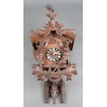 A cuckoo clock contained in a carved wooden case surmounted by a stag, the sides decorated game