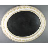 An oval plate wall mirror contained in a gilt and white painted carved frame 32"w x 39"h