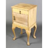 A bleached oak bedside cabinet fitted a drawer above cupboard, raised on cabriole supports 29"h x