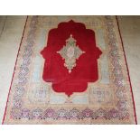 A red and gold ground Persian Kirman carpet with central medallion 161" x 124", some wear The fringe