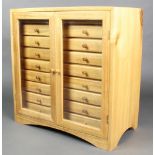 A bleached mahogany table top collectors chest fitted 18 short drawers with tore handles, enclosed