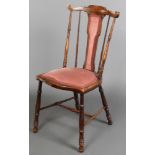 An Edwardian mahogany stick and rail back bedroom chair upholstered in pink Dralon, raised on turned