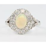 An 18ct white gold opal and diamond cluster ring, the centre stone approx 1.25ct surrounded by 11