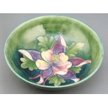 A Walter Moorcroft, a green glazed Columbine pattern circular bowl, the base with signature and