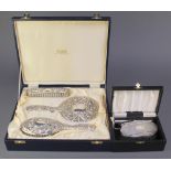 A cased silver hair brush and comb, Birmingham 1983 with a cased repousse silver brush set