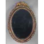 A 19th Century oval plate mirror contained in a decorative carved wooden frame surmounted by a shell