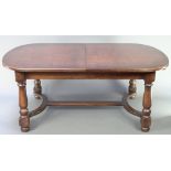 An oak oval extending dining table with 1 extra leaf, raised on 4 turned column supports with Y