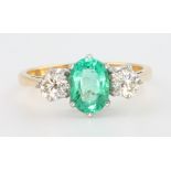 An 18ct yellow gold emerald and diamond 3 stone ring, the centre stone 1.1ct flanked by 2