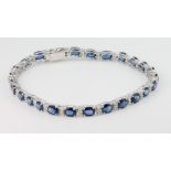 An 18ct white gold sapphire and diamond bracelet, comprising 26 oval cut sapphires interspersed with