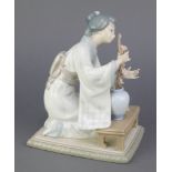 A Lladro figure of a seated Japanese lady arranging flowers in a vase 8 1/2", boxed1 flower stem