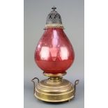 A twin handled brass oil lamp with red glass shade converted for use as an electric table lamp